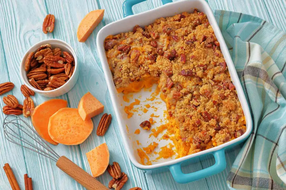 کسرول سیب‌زمینی شیرین در ظرفی آبی، با پکان و لایهٔ پودر، همراه با قطعات سیب‌زمینی شیرین و پکان